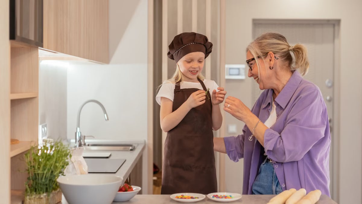 A joyful moment of a grandmother and granddaughter baking sweets in a modern kitchen.